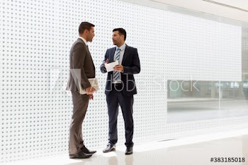 Corporate businessmen with digital tablet talking in modern office