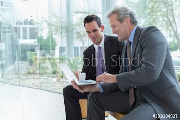 Corporate businessmen with laptop talking in office lobby