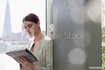 Corporate businesswoman using digital tablet in office window