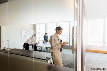 Corporate businesswoman using smart phone in conference room