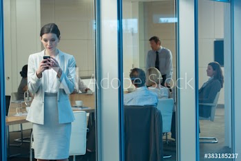 Corporate businesswoman using smart phone in conference room window