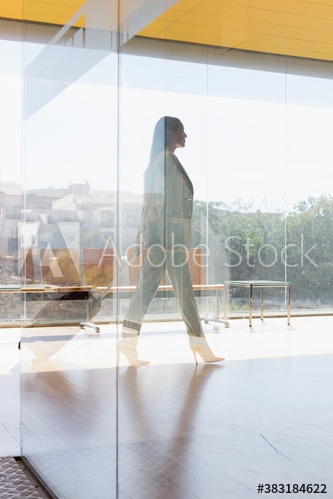 Corporate businesswoman walking in sunny modern office