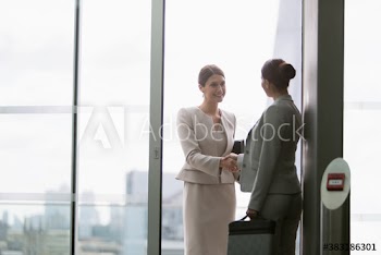 Corporate businesswomen shaking hands in city window