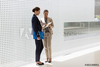 Corporate businesswomen using digital tablet in modern lobby