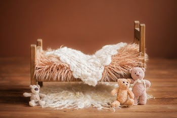 Cot for a newborn on a brown background with toys and a white rug, background for a newborn