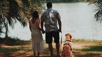 Couple And Dog Standing On Shore
