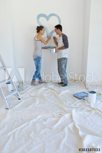 Couple painting blue heart on wall