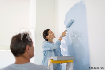 Couple painting wall with blue paint