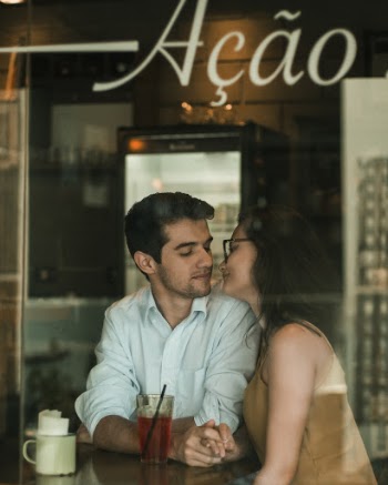 Couple Seated Near Window Holding Hands