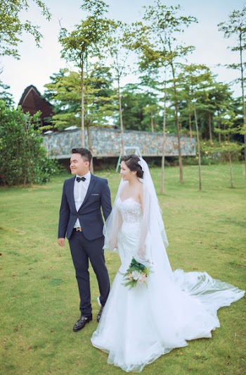 Couple Standing While Wearing Wedding Suits and Dress Near Gray Building