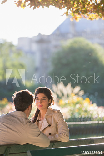 Couple talking on sunny park bench