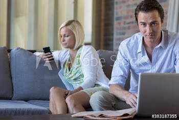 Couple using laptop and smart phone on sofa