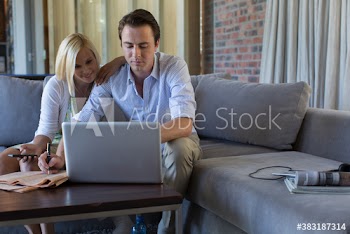 Couple using laptop on sofa