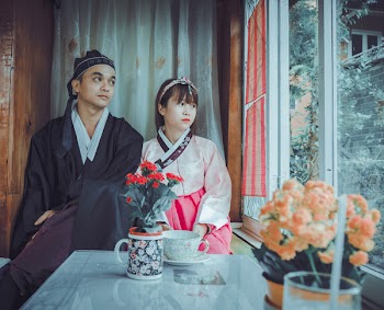 Couple Wearing Korean Traditional Dress Near Windowpane Staring at the Window