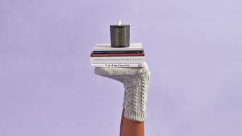 Cozy candle and books, feet, socks. 