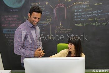 Creative business people brainstorming at computer and blackboard