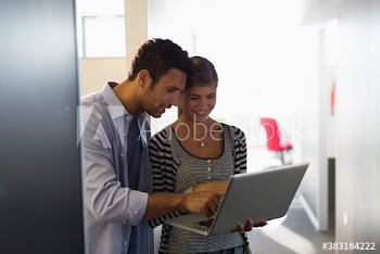 Creative business people using laptop in office corridor