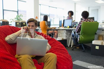 Creative businessman with laptop and smart phone in beanbag chair