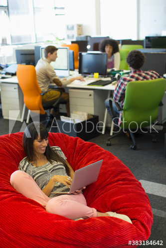 Creative businesswoman with laptop in beanbag chair
