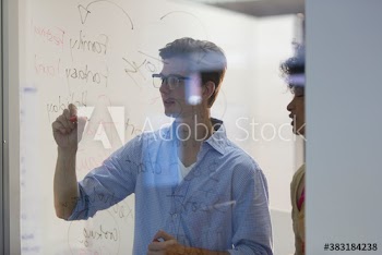 Creative young business people brainstorming at glass in office