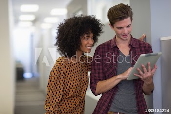 Creative young business people using digital tablet in office corridor