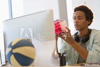 Creative young businessman examining prototype at computer in office