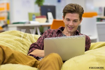Creative young businessman using laptop in beanbag chair