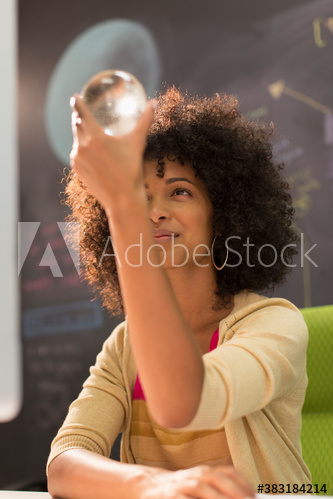 Creative young businesswoman examining orb in office