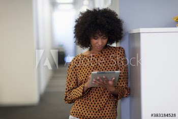 Creative young businesswoman using digital tablet in office corridor