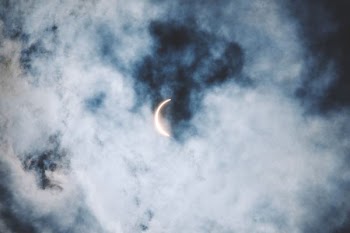 crescent moon under cumulus clouds