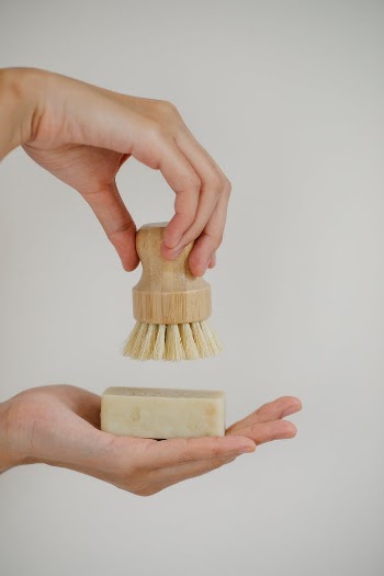 Crop woman with skin care brush and soap bar