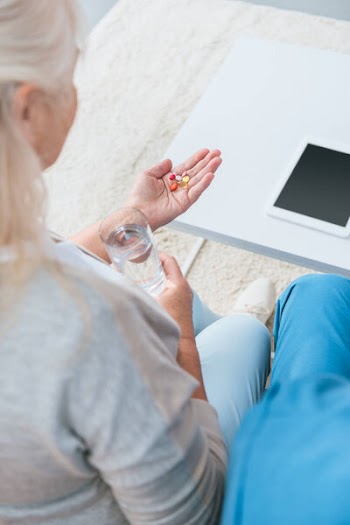 Cropped shot of senior woman holding glass of water and pills