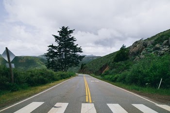 Crosswalk And Road Through Grassy Hills