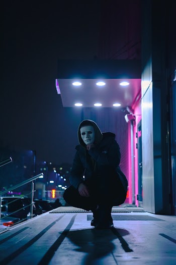 Crouching Man Wearing Black Hoodie at Night