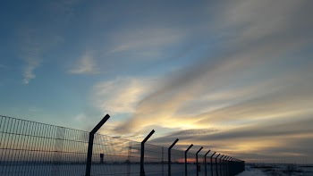 Cumulus Clouds Above Metal Grille Fence