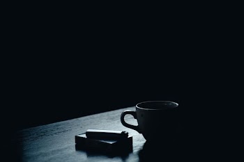 cup near cigarette park and lighter inside dark room