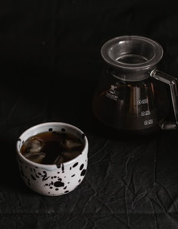 Cup of Black Coffee With Ice Beside Carafe on Table