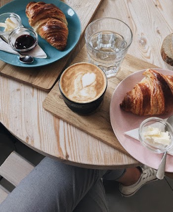 Cup of Latte Between Baked Bread Served on Plate