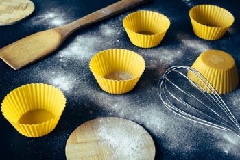 Cupcake molds and kitchenware placed on table with flour · Free Stock Photo