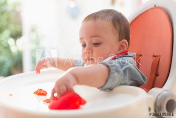 Curious baby boy eating in high chair