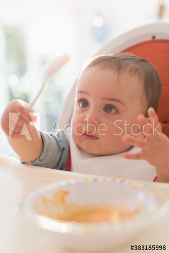 Curious baby boy eating in high chair