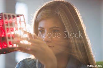 Curious creative young businesswoman examining prototype