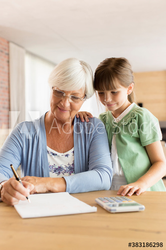 Curious granddaughter watching grandmother budgeting at table
