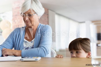 Curious granddaughter watching grandmother paying bills