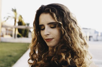 Curly Brown Haired Woman Wearing Black Shirt With Red Lipstick Looking Down