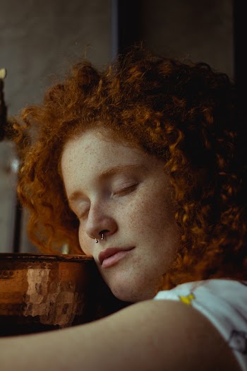 Curly Haired Woman Leaning on Table