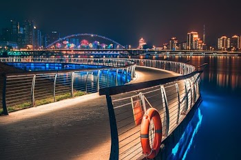 curve road with railings near buildings with lights at night