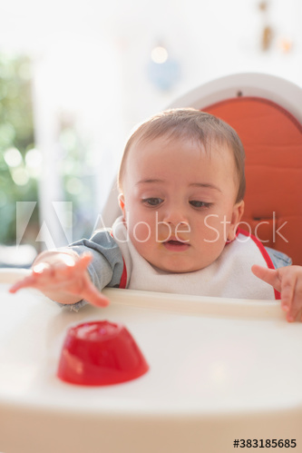 Cute baby boy reaching eating in high chair