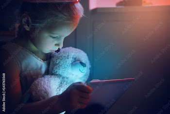 Cute girl hugging bear looking in tablet