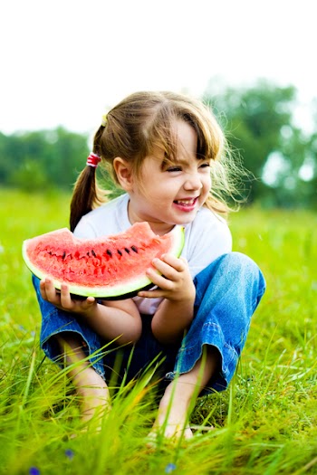 cute little girl eating  water-melon on the grass in summertime